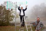 Am Mainufer montiert Oberbürgermeister Jürgen Herzing das Logo "Grünes Rad" an ein Wegweisungsschild.