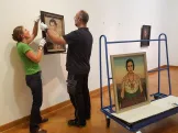 Restauratorin und Museumstechniker hängen vorsichtig die wertvollen Gemälde von Christian Schad ab.