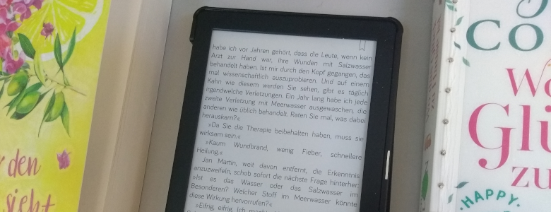 E-Book-Reader neben Büchern im Regal