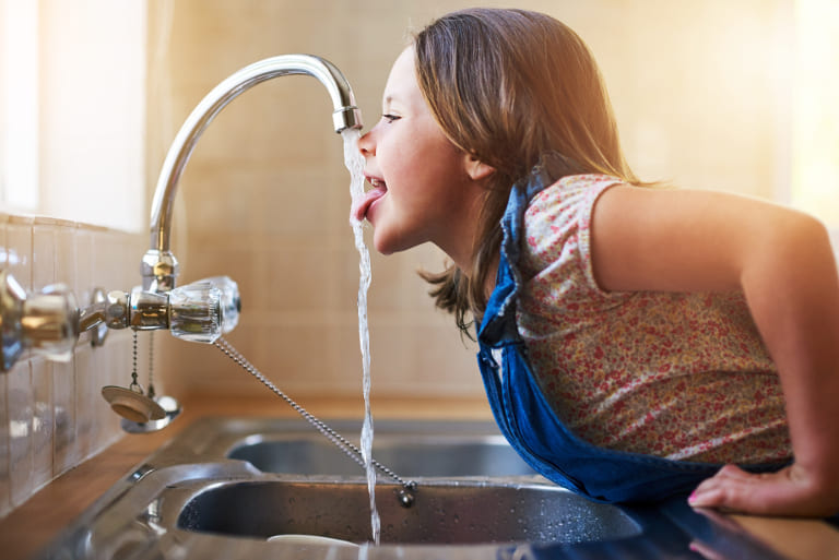 Kind trinkt aus Wasserhahn