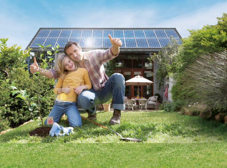 Vater und Tochter im Garten vor Solaranlage