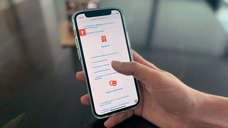 Nutzender mit Smartphone in der Hand, die Website der Stadt Aschaffenburg ist geöffnet.