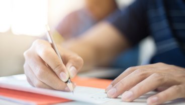Bildausschnitt von Hände einer Person, die gerade mit Bleistift schreibt