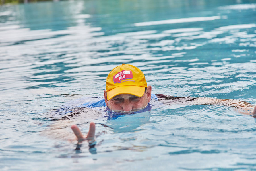 Schwimmbecken mit Mensch, Handzeichen, gelbe Kappe