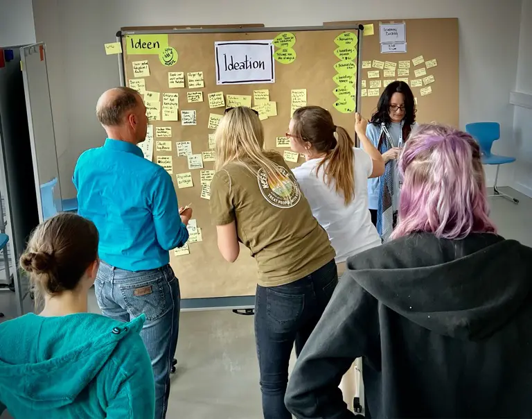 IMG_2264 Mehrere Teilnehmende betrachten eine Wand mit Post-Its.
