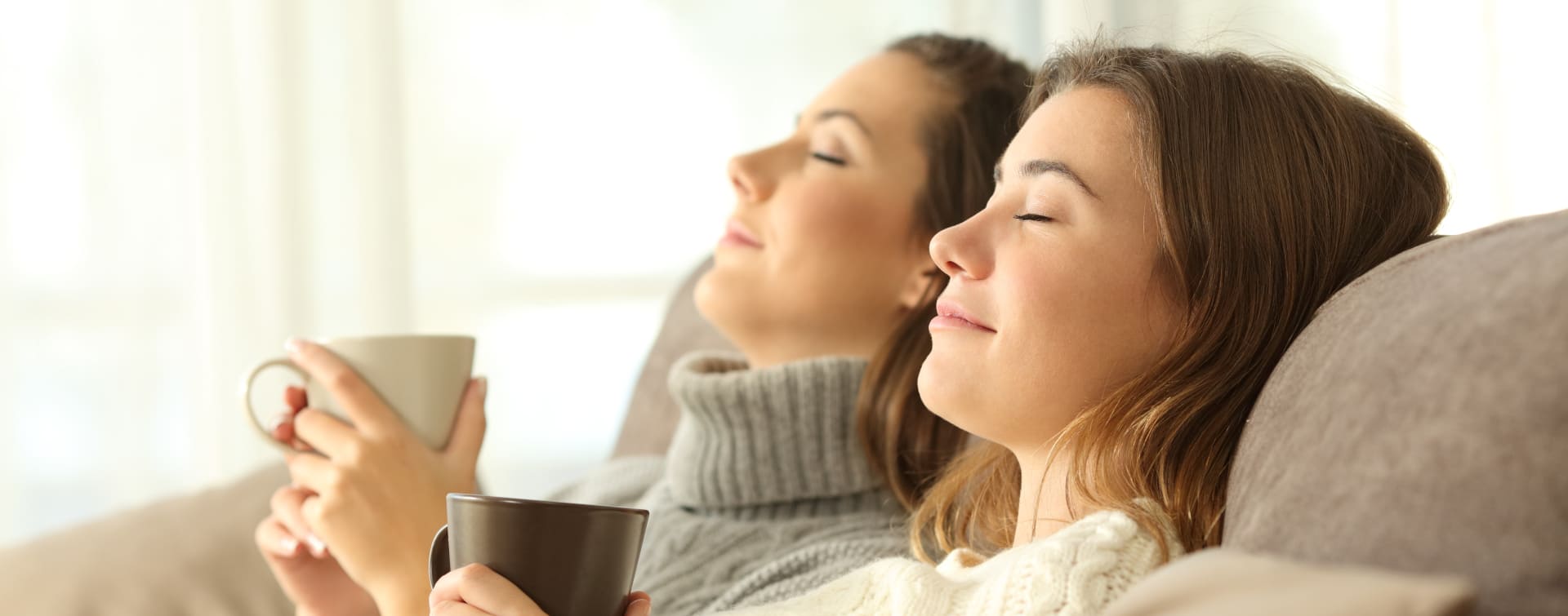 Frauen sitzen auf Sofa mit Tasse