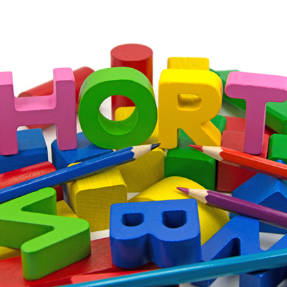 Bunte Buchstaben und Buntstifte liegen durcheinander, die Buchstaben formen das Wort HORT.