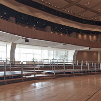 Kirchner Saal der Stadthalle am Schloss mit Empore, Podesten und Blick ins Foyer mit großer Fensterfront.