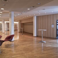 Foyer des Tagungscenters in der Stadthalle am Schloss mit Garderobe, Stehtischen und Sitzgruppe.