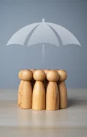 Das Foto zeigt sieben Spielfiguren aus Holz die eng im Kreis stehen. Über sie ist ein Schirm gespannt.