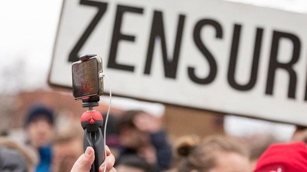 02.03.2019, Berlin: „Zensur" ist bei einer Demonstration des Bündnisses «Berlin gegen 13» gegen Uploadfilter und EU-Urheberrechtsreform im Artikel 13 auf einem Plakat zu lesen, während ein Teilnehmer mit einem Handy filmt.  | Bild: picture alliance/dpa | Christoph Soeder