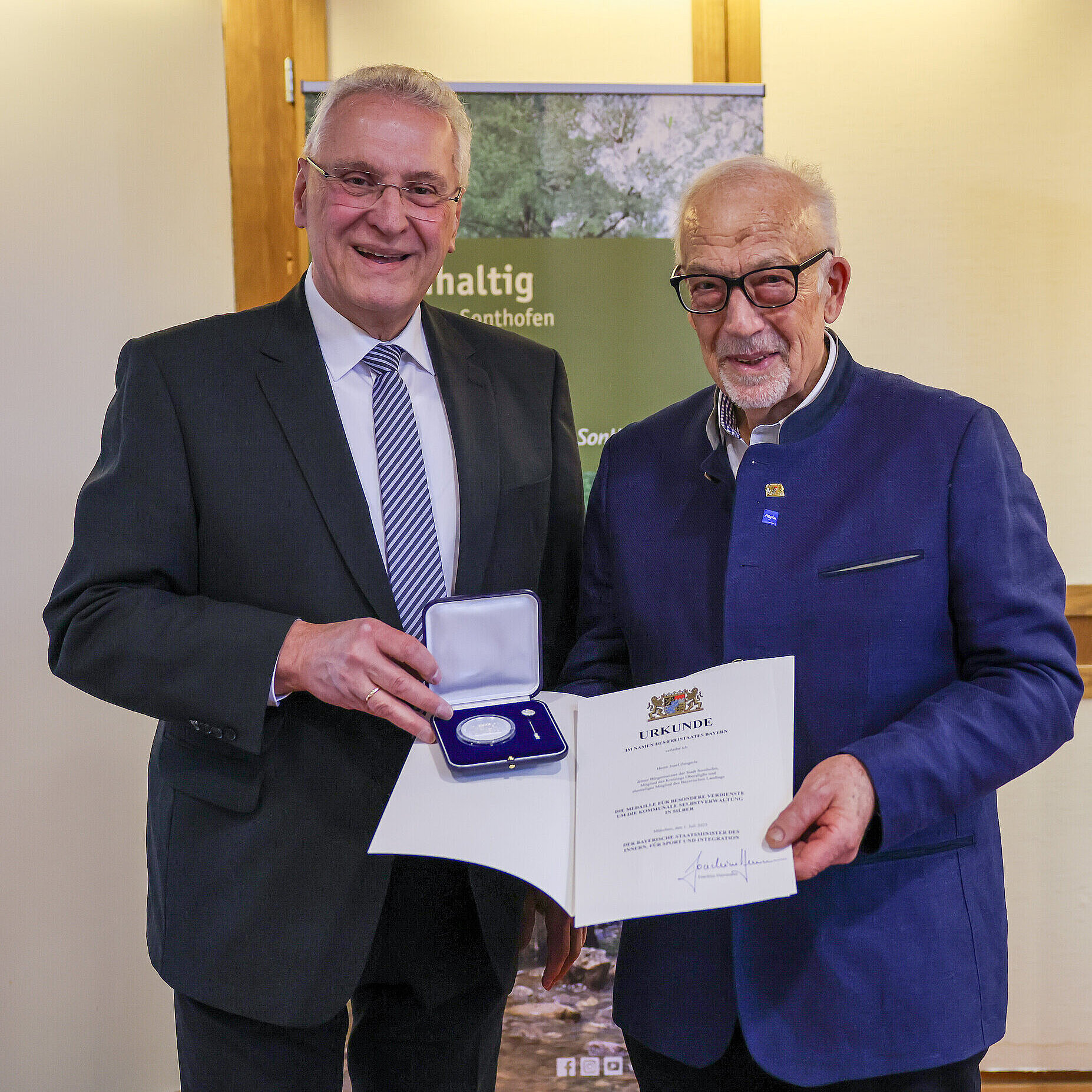 Innenminister Joachim Herrmann neben MdL a.D. Josef Zengerle mit Medaille in Silber und Urkunde