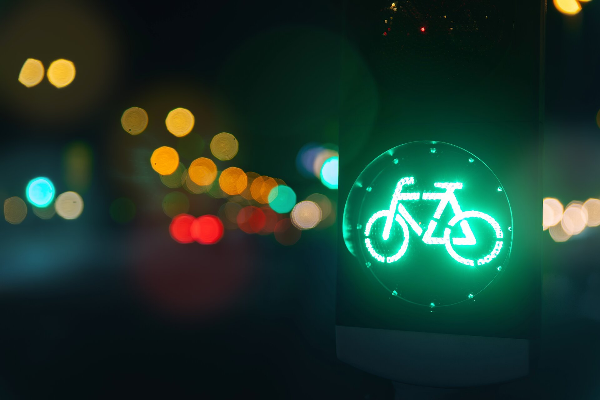 grüne Fahrradampel bei Nacht mit Straßenbeleuchtung im Hintergrund